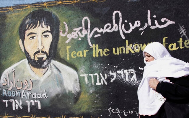 Une Palestinienne passe devant une peinture murale réalisée par un artiste du Hamas représentant le soldat israélien capturé Ron Arad, dans le camp de réfugiés de Jabalia, dans la bande de Gaza, le 28 janvier 2010. (Crédit : Abed Rahim Khatib/Flash90) Une Palestinienne passe devant une peinture murale réalisée par un artiste du Hamas représentant le soldat israélien capturé Ron Arad, dans le camp de réfugiés de Jabalia, dans la bande de Gaza, le 28 janvier 2010. (Crédit : Abed Rahim Khatib/Flash90)
