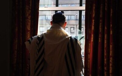 Le Premier ministre Naftali Bennett récite les prières du matin à son hôtel à Washington, le 25 août 2021. (Crédit : Avi Ohayon/GPO)