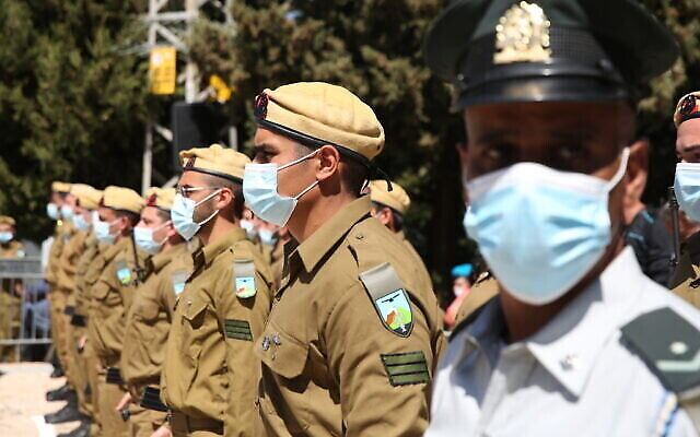Des soldats israéliens portant des masques lors de Yom HaZikaron, au cimetière militaire de Tzfat, le 14 avril 2021. (Crédit : David Cohen/Flash90) Des soldats israéliens portant des masques lors de Yom HaZikaron, au cimetière militaire de Tzfat, le 14 avril 2021. (Crédit : David Cohen/Flash90)