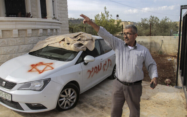 Un Palestinien devant des slogans écrits en hébreu dans le village de Marda en Cisjordanie, le 13 octobre 2021. (Crédit : Nasser Ishtayeh/Flash90)