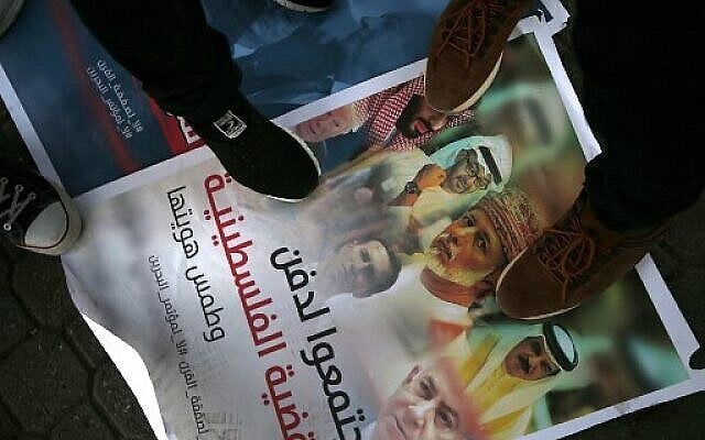 Des Palestiniens marchent sur une pancarte affichant des photos du prince héritier d'Abou Dhabi, Cheikh Mohammed bin Zayed, du prince héritier saoudien Mohammed bin Salman, du roi de Bahreïn Hamad al-Khalifa, du Sultan Qaboos d'Oman à Muscat, du Premier ministre Benjamin Netanyahu, du président américain Donald Trump et de son gendre et conseiller Jared Kushner, lors d'une manifestation dénonçant la conférence Peace to Prosperity organisée par les États-Unis à Bahreïn, dans la ville de Gaza, le 24 juin 2019. (Crédit : MOHAMMED ABED / AFP) Des Palestiniens marchent sur une pancarte affichant des photos du prince héritier d'Abou Dhabi, Cheikh Mohammed bin Zayed, du prince héritier saoudien Mohammed bin Salman, du roi de Bahreïn Hamad al-Khalifa, du Sultan Qaboos d'Oman à Muscat, du Premier ministre Benjamin Netanyahu, du président américain Donald Trump et de son gendre et conseiller Jared Kushner, lors d'une manifestation dénonçant la conférence Peace to Prosperity organisée par les États-Unis à Bahreïn, dans la ville de Gaza, le 24 juin 2019. (Crédit : MOHAMMED ABED / AFP)