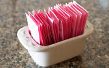Illustration : Un récipient contenant des sachets d'édulcorant artificiel (Crédit : BigRedCurlyGuy ; iStock by Getty Images)