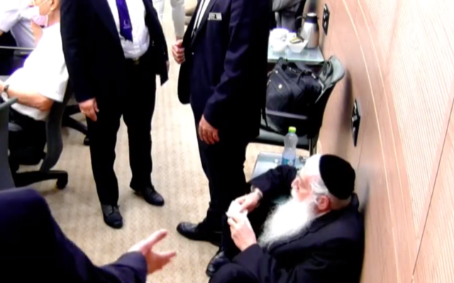 Le député de Yahadout HaTorah Meir Porush, assis par terre, récite des Psaumes pendant une réunion de la Knesset en protestation contre le député travailliste Gilad Kariv, le 7 octobre 2021. (Capture d'écran/Twitter) Le député de Yahadout HaTorah Meir Porush, assis par terre, récite des Psaumes pendant une réunion de la Knesset en protestation contre le député travailliste Gilad Kariv, le 7 octobre 2021. (Capture d'écran/Twitter)