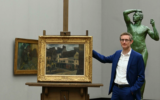 Ralph Gleis, historien de l'art et directeur de galerie allemand, se tenant devant un tableau de Pissarro spolié par les nazis, le 18 octobre 2021. (Crédit : Christof Stache/AFP)