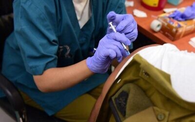 Sur cette photo publiée par les Forces de défense israéliennes le 31 août 2021, un soldat reçoit une injection de rappel du vaccin contre le coronavirus. (Crédit : Tsahal)