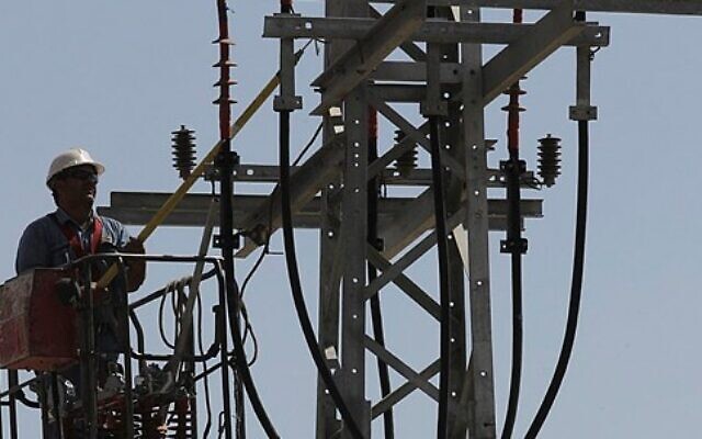 Image illustrative d'un ouvrier d'Israel Electric Corporation hissé par une grue sur un poteau électrique pour effectuer des travaux de maintenance, à l'extérieur de Jérusalem, le 10 juin 2013. (Crédit : Flash 90)