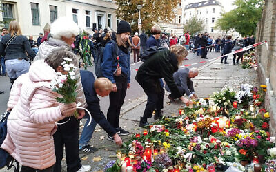 Des personnes déposent des fleurs devant la synagogue de Halle, en Allemagne, où un mémorial a été placé pour les victimes de la fusillade de mercredi. Le 11 octobre 2019. (Yaakov Schwartz/ Times of Israel)