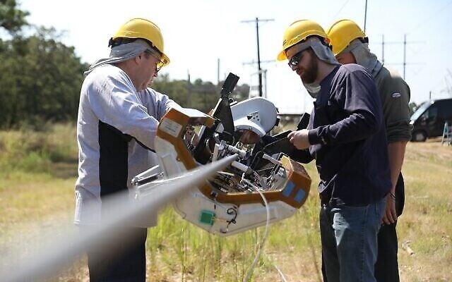 Des ouvriers installent le robot Bombyx de Facebook qui se déplace le long des lignes électriques, les enveloppant de câbles en fibre optique, afin de déployer l'Internet en fibre optique dans les communautés. (Facebook) Des ouvriers installent le robot Bombyx de Facebook qui se déplace le long des lignes électriques, les enveloppant de câbles en fibre optique, afin de déployer l'Internet en fibre optique dans les communautés. (Facebook)