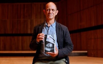 L'auteur sud-africain Damon Galgut pose avec son livre "The Promise", le 31 octobre 2021. (Crédit : Tolga Akmen / AFP)