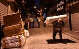 Un porteur porte des affaires dans une rue tandis que d'autres attendent leur tour tôt le matin, le 28 octobre 2021, près du Grand Bazar d'Istanbul. (Crédit : Ozan KOSE / AFP)