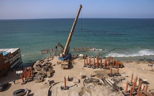 Une grue est utilisée pour déployer des échasses pour la construction d'une nouvelle jetée et d'un bâtiment de restauration le long du bord de mer méditerranéen dans la ville de Gaza, le 27 octobre 2021. (Crédit : MOHAMMED ABED / AFP) Une grue est utilisée pour déployer des échasses pour la construction d'une nouvelle jetée et d'un bâtiment de restauration le long du bord de mer méditerranéen dans la ville de Gaza, le 27 octobre 2021. (Crédit : MOHAMMED ABED / AFP)