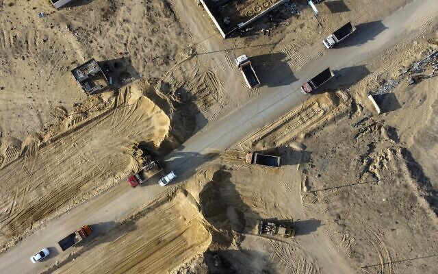 Des camions portant des plaques d'immatriculation égyptiennes et des excavatrices défrichent un terrain pour l'extension d'une route dans un site au nord de la ville de Gaza, le 30 octobre 2021. (Crédit : MOHAMMED ABED / AFP)