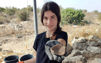 Une étudiante tient une trouvaille provenant des fouilles de la forêt de Lachish. (Crédit : Tzachi Zisso)