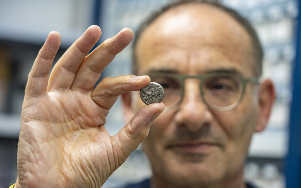 Le docteur Robert Kool avec une pièce en argent rare. (Crédit : Yaniv Berman/Cité de David et Autorité israélienne des antiquités)