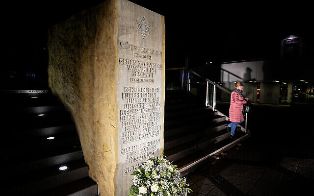 Une femme devant une stèle commémorative où se tenait l'ancienne synagogue avant qu'elle ne soit détruite par les nazis en 1938 à Dortmund, en Allemagne, le 9 novembre 2021. (Crédit : AP Photo/Martin Meissner)