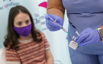 Jamie Onofrio Franceschini, 11 ans, avec l'infirmière Rosemary Lantigua qui prépare une seringue avec la première dose du vaccin Pfizer-BioNTech COVID-19 pour les enfants de 5 à 12 ans à l'hôpital pour enfants de Montefiore, le 3 novembre 2021, dans le quartier du Bronx à New-York. (Crédit : AP/Mary Altaffer)