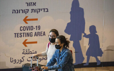 Des voyageurs portant le masque arrivent à l'aéroport Ben-Gurion après qu'Israël a interdit l'entrée des ressortissants étrangers pour contrer l'apparition d'un nouveau variant du coronavirus, le 28 novembre 2021. (Crédit : AP Photo/Ariel Schalit)