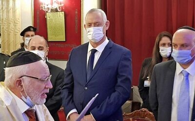 Le ministre israélien de la Défense Benny Gantz écoute une prière de Gavriel Dery, membre de la communauté juive locale, lors d'une visite à la synagogue Talmud Torah de Rabat, le 25 novembre 2021. (Crédit : Jonah MANDEL / AFP)