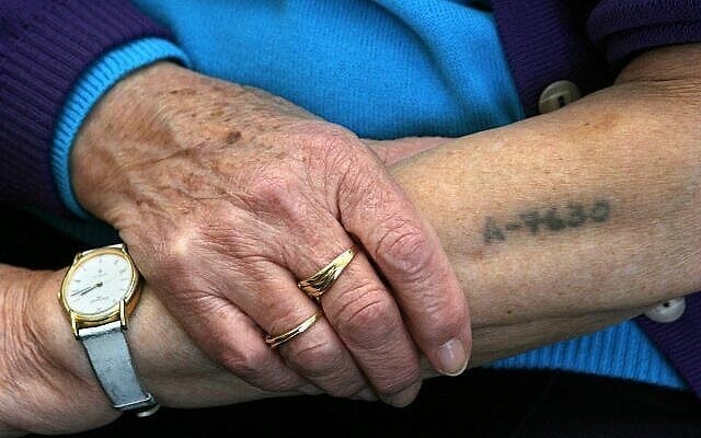 Bracha Ghilai, 75 ans, survivante de la Shoah, montre son bras tatoué dans sa maison à Holon près de Tel Aviv, le 23 janvier 2005. (Crédit : AP/Ariel Schalit)