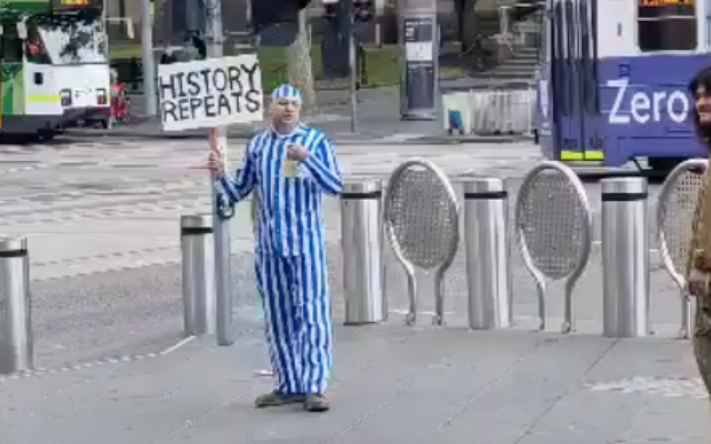 Capture d'écran de la vidéo d'un homme vêtu d'une tenue rappelant un détenu de camp de concentration de la Shoah alors qu'il proteste contre les vaccinations COVID-19 et les lois sur la santé à Melbourne en Australie, le 30 octobre 2021. (Crédit : Commission Anti-Diffamation) Capture d'écran de la vidéo d'un homme vêtu d'une tenue rappelant un détenu de camp de concentration de la Shoah alors qu'il proteste contre les vaccinations COVID-19 et les lois sur la santé à Melbourne en Australie, le 30 octobre 2021. (Crédit : Commission Anti-Diffamation)