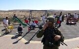 Un soldat israélien se tient à l'écart alors que des habitants d’implantation israéliens pénètrent sur un terrain de jeu palestinien à Susiya, un hameau palestinien de Cisjordanie, le samedi 6 novembre 2021 (Crédit : Guy Butuvia).