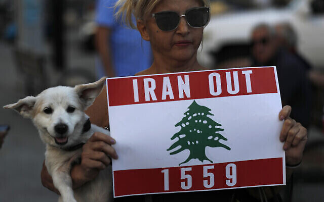 Une manifestante libanaise porte son chien et tient une pancarte lors d'une manifestation contre le groupe terroriste Hezbollah et la visite du ministre iranien des Affaires étrangères Hossein Amir-Abdollahian, Beyrouth, Liban, 6 octobre 2021. (AP Photo/Hussein Malla) Une manifestante libanaise porte son chien et tient une pancarte lors d'une manifestation contre le groupe terroriste Hezbollah et la visite du ministre iranien des Affaires étrangères Hossein Amir-Abdollahian, Beyrouth, Liban, 6 octobre 2021. (AP Photo/Hussein Malla)