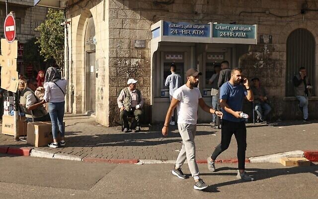 Des Palestiniens marchent devant un comptoir de change dans la ville de Ramallah, en Cisjordanie, le 5 octobre 2021. (ABBAS MOMANI / AFP) Des Palestiniens marchent devant un comptoir de change dans la ville de Ramallah, en Cisjordanie, le 5 octobre 2021. (ABBAS MOMANI / AFP)