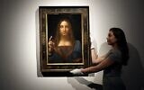 Sur cette photo du 24 octobre 2017, un employé pose avec le "Salvator Mundi" de Léonard de Vinci exposé dans les salles de vente de Christie's à Londres. (AP Photo/Kirsty Wigglesworth)