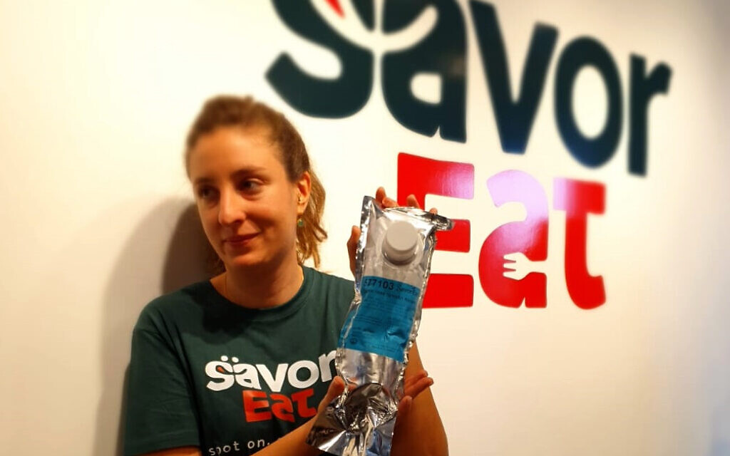 Une employée de SavorEat présente une cartouche contenant les ingrédients à base de plantes pour le produit "bœuf" de l'entreprise. La cartouche est insérée dans le 'robot' chef, la technologie de fabrication additive de SavorEat, pour fabriquer les galettes. Novembre 2021. (Personnel du Times of Israel)