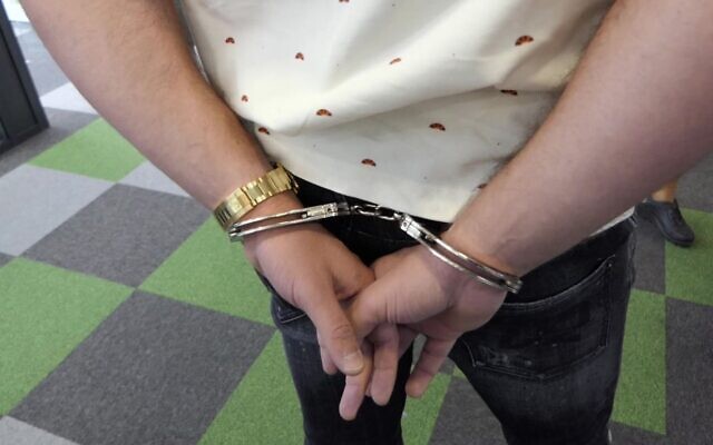 L'employé du centre d'appels Dortome BG, en Bulgarie, est menotté pendant un raid coordonné par Europol, le 6 octobre 2021. (Crédit : Ministère bulgare de l'Intérieur)