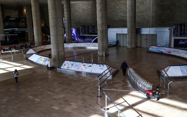 Un employé de l'aéroport fait rouler des chariots à bagages dans un hall désert de l'aéroport international israélien Ben Gourion de Lod, près de Tel Aviv, le 25 janvier 2021. (Crédit : Emmanuel DUNAND / AFP) Un employé de l'aéroport fait rouler des chariots à bagages dans un hall désert de l'aéroport international israélien Ben Gourion de Lod, près de Tel Aviv, le 25 janvier 2021. (Crédit : Emmanuel DUNAND / AFP)