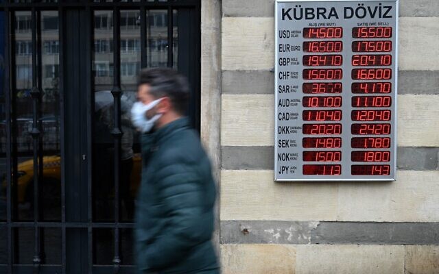 Un homme marche devant un écran affichant les taux contre la livre turque près d'une agence de change à Kaarakoy à Istanbul, le 16 décembre 2021 à Istanbul. (Crédit : Ozan KOSE / AFP) Un homme marche devant un écran affichant les taux contre la livre turque près d'une agence de change à Kaarakoy à Istanbul, le 16 décembre 2021 à Istanbul. (Crédit : Ozan KOSE / AFP)