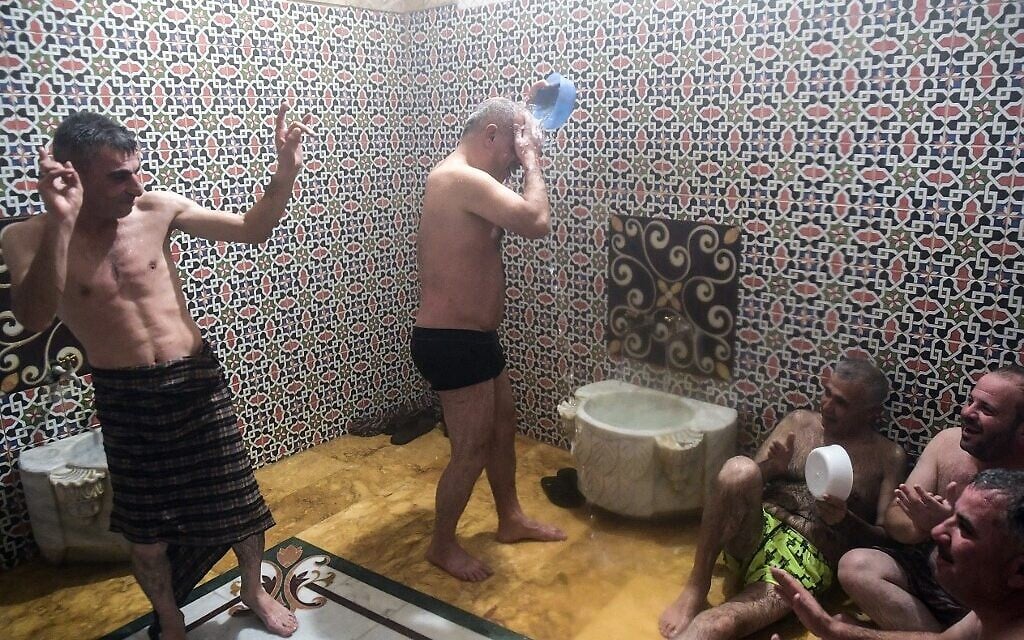 Des hommes se baignent à Hammam al-Qawas, un bain turc traditionnel, dans la ville d'Alep, au nord de la Syrie, le 16 décembre 2021. (Crédit : AFP)