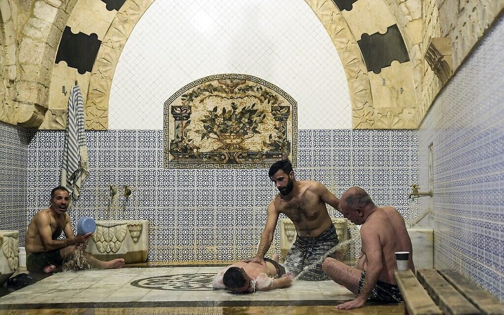 Des hommes se baignent à Hammam al-Qawas, un bain turc traditionnel, dans la ville d'Alep, au nord de la Syrie, le 16 décembre 2021. (Crédit : AFP)