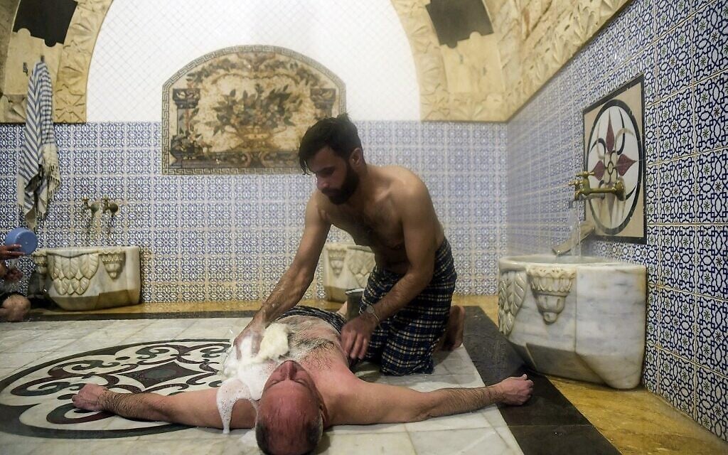 Des hommes se baignent à Hammam al-Qawas, un bain turc traditionnel, dans la ville d'Alep, au nord de la Syrie, le 16 décembre 2021. (Crédit : AFP)