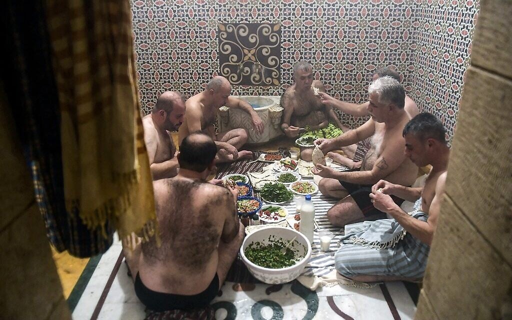 Des hommes déjeunent après s'être baignés à Hammam al-Qawas, un bain turc traditionnel, dans la ville d'Alep, au nord de la Syrie, le 16 décembre 2021. (Crédit : AFP)