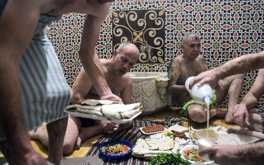Des hommes déjeunent après s'être baignés à Hammam al-Qawas, un bain turc traditionnel, dans la ville d'Alep, au nord de la Syrie, le 16 décembre 2021. (Crédit : AFP)