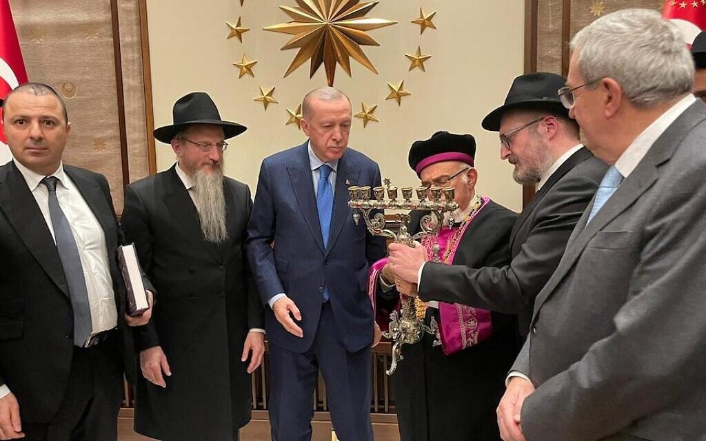 Les membres de l'Alliance des rabbins des États islamiques (ARIS) offrent au président turc Recep Tayyip Erdogan une ménorah décorée au nom de la communauté juive de Turquie pendant une rencontre au palais présidentiel d'Ankara, le 23 décembre 2021. De gauche à droite : Akif Gilalov, chef du Congrès mondial des Juifs des montagnes ; Berel Lazar, grand-rabbin de Russie ; Erdogan; Isak Haleva, grand rabbin séfarade de Turquie; le rabbin Mendy Chitrik, directeur de l'ARIS; Erol Kohen, président de la communauté juive turque. (Crédit : David I. Klein/JTA) Les membres de l'Alliance des rabbins des États islamiques (ARIS) offrent au président turc Recep Tayyip Erdogan une ménorah décorée au nom de la communauté juive de Turquie pendant une rencontre au palais présidentiel d'Ankara, le 23 décembre 2021. De gauche à droite : Akif Gilalov, chef du Congrès mondial des Juifs des montagnes ; Berel Lazar, grand-rabbin de Russie ; Erdogan; Isak Haleva, grand rabbin séfarade de Turquie; le rabbin Mendy Chitrik, directeur de l'ARIS; Erol Kohen, président de la communauté juive turque. (Crédit : David I. Klein/JTA)