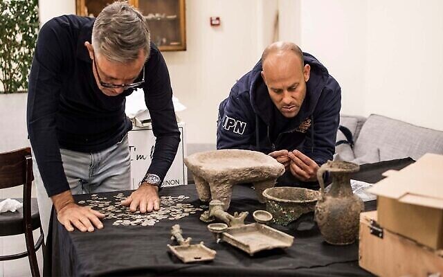 Des enquêteurs examinent des objets saisis par la police qui datent probablement de la révolte de Bar Kochba contre les Romains. (Crédit : Yoli Schwartz/Israel Antiquities Authority) Des enquêteurs examinent des objets saisis par la police qui datent probablement de la révolte de Bar Kochba contre les Romains. (Crédit : Yoli Schwartz/Israel Antiquities Authority)