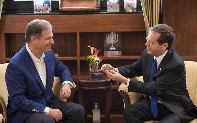 Le président Isaac Herzog, à gauche, présente à l'astronaute israélien Eytan Stibbe un cube en verre portant une prière pour le bien-être de l'État d'Israël, à la résidence du président à Jérusalem, le 16 décembre 2021. (Crédit : Kobi Gideon/GPO)