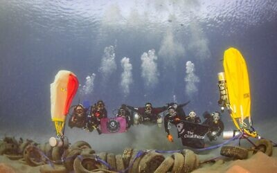 Des bénévoles de l'ONG Coast Patrol à  Eilat prennent la pose avec des pneus trouvés dans les fonds marins lors d'une opération de nettoyage annuelle. (Crédit : 'Amit Liber)