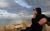 Bilal Moussa, 34 ans, candidat à l'émigration, fume une cigarette en marchant au bord de la mer à Tripoli, au nord de Beyrouth, le 9 décembre 2021. (Crédit : JOSEPH EID / AFP)