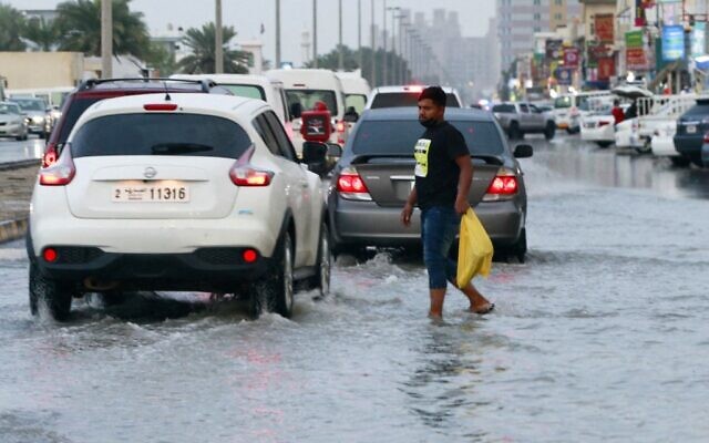 Un homme marche dans une rue inondée dans l'émirat de Sharjah, dans le Golfe, après de fortes pluies, aux Émirats arabes unis, le 1er janvier 2022. (Crédit : AFP)