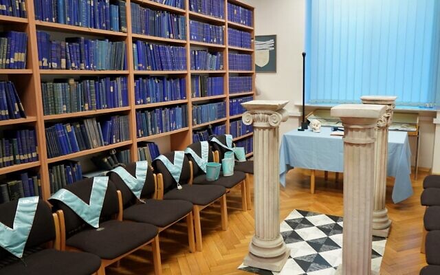 Des colliers maçonniques à côté d'étagères de livres à la bibliothèque universitaire de Poznan, qui abrite des archives historiques de la franc-maçonnerie en Europe amassées par les nazis, à Poznan, dans l'ouest de la Pologne, le 22 décembre 2021. (Crédit : JANEK SKARZYNSKI / AFP) Des colliers maçonniques à côté d'étagères de livres à la bibliothèque universitaire de Poznan, qui abrite des archives historiques de la franc-maçonnerie en Europe amassées par les nazis, à Poznan, dans l'ouest de la Pologne, le 22 décembre 2021. (Crédit : JANEK SKARZYNSKI / AFP)