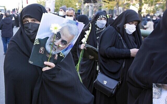 Des Iraniens tiennent une photo du haut commandant iranien Qasem Soleimani à Téhéran lors d'une procession funéraire pour 150 soldats iraniens tués pendant la guerre Iran-Irak (1980-1988), dont les corps ont été récupérés sur les champs de bataille, le 6 janvier 2022. (Crédit : AFP) Des Iraniens tiennent une photo du haut commandant iranien Qasem Soleimani à Téhéran lors d'une procession funéraire pour 150 soldats iraniens tués pendant la guerre Iran-Irak (1980-1988), dont les corps ont été récupérés sur les champs de bataille, le 6 janvier 2022. (Crédit : AFP)