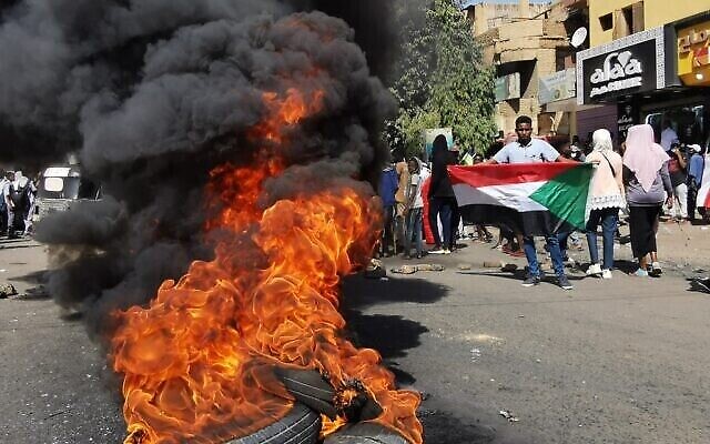 Des manifestants soudanais devant des pneus en feu lors d'un rassemblement pour protester contre le coup d'État militaire d'octobre 2021, dans la capitale Khartoum, le 9 janvier 2022. (Crédit : AFP) Des manifestants soudanais devant des pneus en feu lors d'un rassemblement pour protester contre le coup d'État militaire d'octobre 2021, dans la capitale Khartoum, le 9 janvier 2022. (Crédit : AFP)