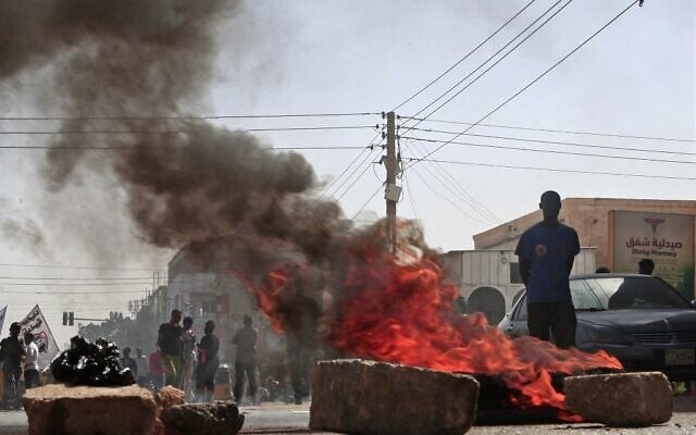 Des manifestants soudanais brandissent des drapeaux nationaux alors qu'ils protestent contre le coup d'État militaire d'octobre 2021, dans la capitale Khartoum, le 17 janvier 2022. (Crédit : AFP) Des manifestants soudanais brandissent des drapeaux nationaux alors qu'ils protestent contre le coup d'État militaire d'octobre 2021, dans la capitale Khartoum, le 17 janvier 2022. (Crédit : AFP)
