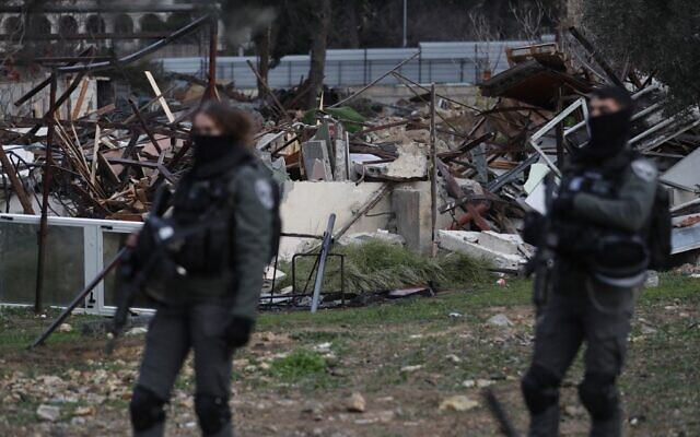 Les forces israéliennes devant les ruines d'une maison palestinienne démolie dans le quartier de Sheikh Jarrah à Jérusalem, le 19 janvier 2022. (Crédit : Ahmad Gharabli/AFP)