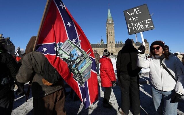 Un manifestant porte un drapeau confédéré américain lors de la manifestation du Convoi de la liberté contre l'obligation vaccinale contre le COVID-19, devant le Parlement canadien à Ottawa, le 29 janvier 2022. (Crédit : Dave Chan/AFP)