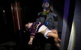 Un secouriste transportant un enfant à la suite d'une attaque présumée à l'arme chimique dans la ville rebelle de Douma, près de Damas, en Syrie, le 8 avril 2018. (Crédit : Casques blancs de la défense civile syrienne via AP)